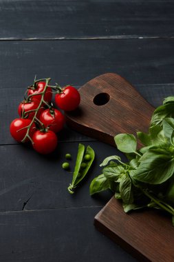 sağlıklı çiğ sebze gıda arka plan olarak ahşap masa, domates, bezelye ve fesleğen yaprakları üzerinde 