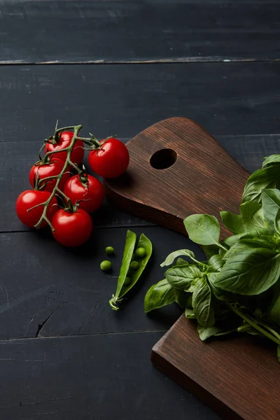 sağlıklı çiğ sebze gıda arka plan olarak ahşap masa, domates, bezelye ve fesleğen yaprakları üzerinde 