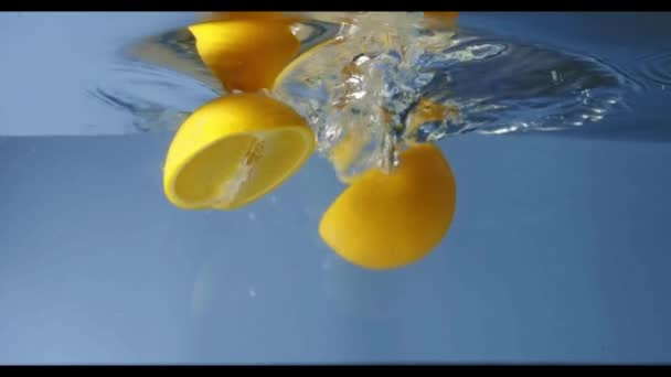 一块新鲜的柠檬落在蓝色背景与水 — 图库视频影像