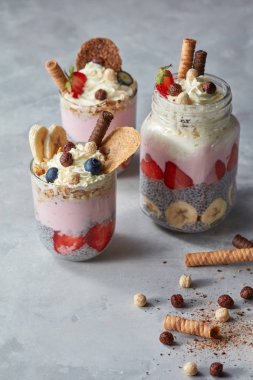 Chia tohum yoğurt, çilek, bisküvi ve muz bir beton zemin üzerine gözlük ile sağlıklı tatlı yaptı. Metin için boş alan.