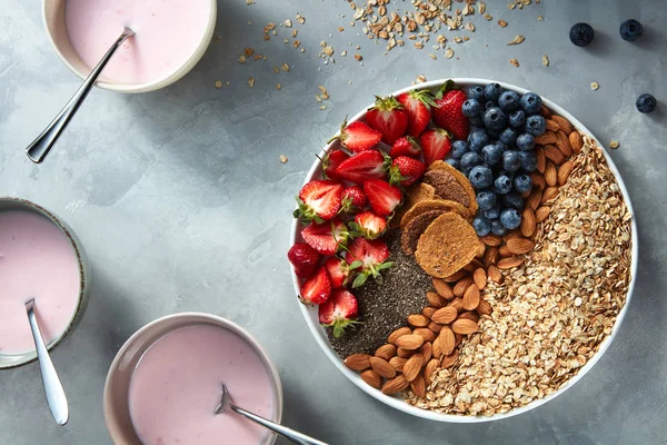Yararlı maddeler kase yoğurt arasında kahvaltı yapmak için chia, çilek ve yulaf ezmesi taş bir plaka üzerinde ışık arka plan. Antioksidan, superfood, kahvaltı üstten görünüm için ideal