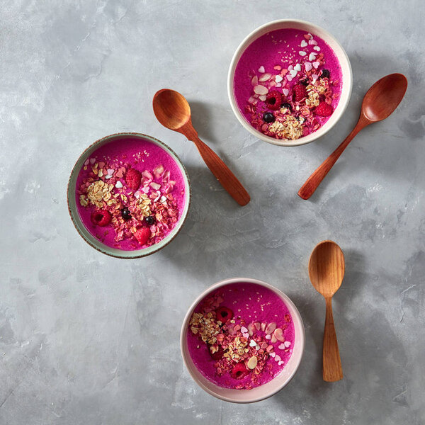 smoothie with granola, beetroot  and berries in ceramic bowls with wooden spoons, healthy breakfast 