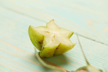 Makro fotoğraf organik Asya meyve, carambola yalanlar üzerine bir ışık yeşil ahşap arka plan yarısı