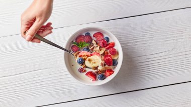 kadın lezzetli sağlıklı organik kahvaltı. Ev yapımı doğal gıda seramik beyaz kase beyaz bir tablo. Doğal organik sağlıklı beslenme kavramı.