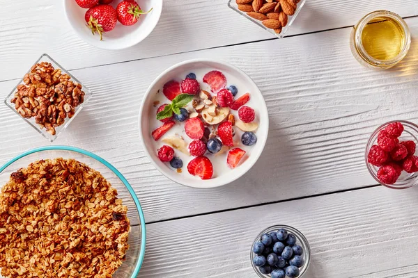 A ready breakfast of natural organic ingredients - granola, berries, muesli, nuts, honey, milk for the preparation of natural healthy food. Concept of organic eating.