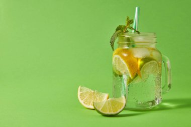 Cam kavanoz ev yapımı köpüklü alkolsüz içecek yeşil bir arka plan üzerinde plastik saman ile yeşil bir tablo. Soğuk yaz alkollü veya alkolsüz içecekler kavramı.