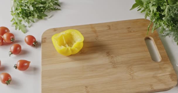 トマト 黄パプリカ チーズ 白いキッチン テーブルに新鮮なハーブ サラダ 女性の料理の新鮮な食材 木の板の半分 — ストック動画