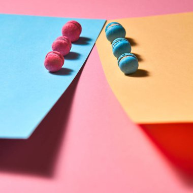 Makaronların renkli bileşimi. Sarı pembe kağıt arka plan üzerinde, tüm mavi macaroons ve gölgeler bir yansıması ile kırık bir macaroon. Üstte görüntü
