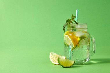 mason cam buz, kireç, limon, yeşil nane plastik saman ile dilimleri ile ev yapımı köpüklü kokteyl yeşil bir tablo. Soğuk yaz alkollü veya alkolsüz içecekler kavramı.