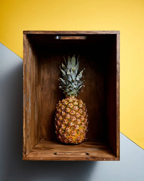 中央组成与一个热带菠萝水果单在木制老式老盒子上双色调黄色灰色背景 顶部视图 — 图库照片