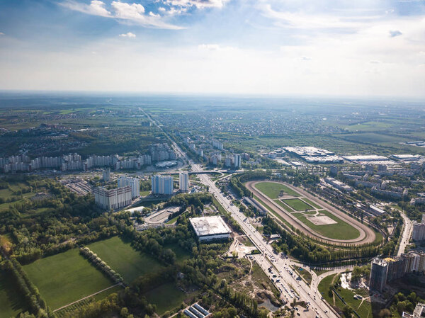 Panoramic view of the city of Kiev with a racetrack, parks with an ice stadium and modern houses against a blue sky on a spring day. District Holosiivskyi. Photo from the drone