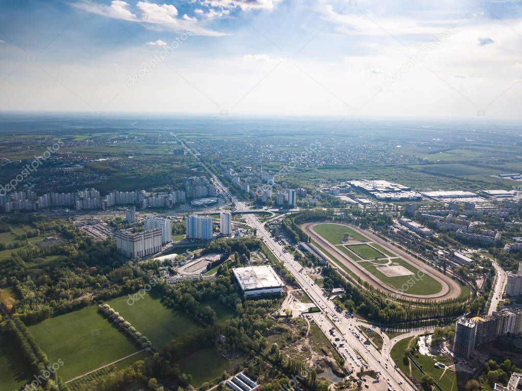 Panoramic view of the city of Kiev with a racetrack, parks with an ice stadium and modern houses against a blue sky on a spring day. District Holosiivskyi. Photo from the drone