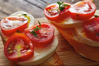 Ahşap kesme tahtası üzerinde geleneksel İtalyan bruschetta - cherry domates, krem peynir, fesleğen yaprakları