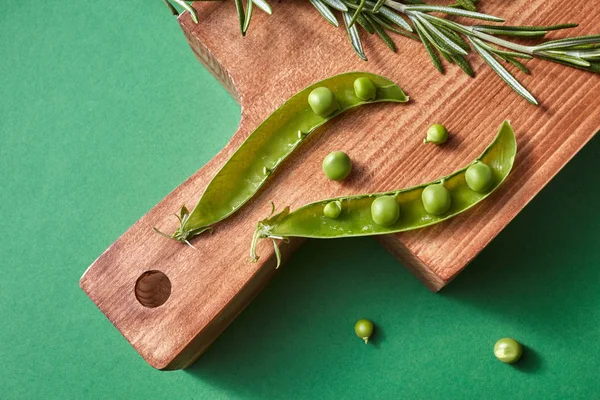 グリーン ピースと食べ物の背景に木の板にローズマリー — ストック写真