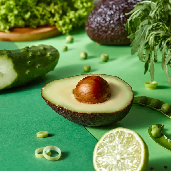 Die Hälfte Der Avocado Mit Knochen Fokus Und Anderes Grünes — Stockfoto