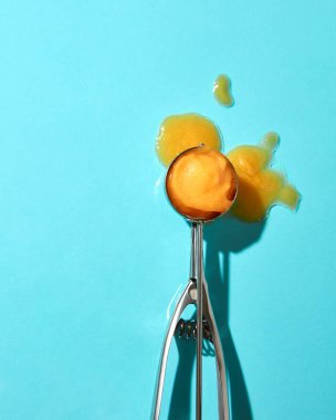  metal kaşık mavi zemin üzerine sarı dondurma topu