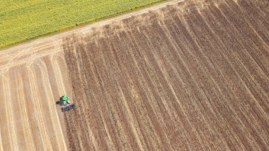 Panoramic view of tractor plowing the soil after harvesting on the field. Aerial view from the drone of the field after harvest. Top view clipart