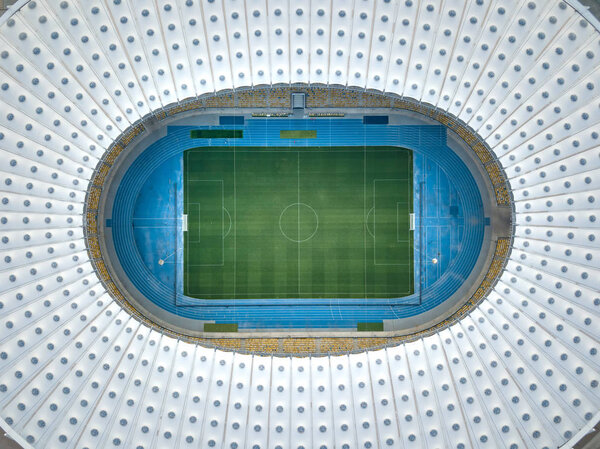 КИЕВ, Украина - 19 июля 2018 года. Вид сверху прямо над футбольным стадионом Национальный спортивный комплекс "Олимпийский" с крышей стадиона, зеленым футбольным полем, трибунами. Вид с воздуха с беспилотника
.