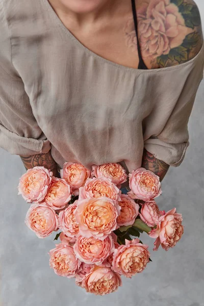 美丽的花束在女孩的手与纹身在灰色背景 顶部视图 — 图库照片