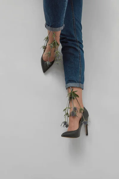 ブルー ジーンズと靴かかとの灰色のテキストで女性の足を美しい花エリンジウム — ストック写真