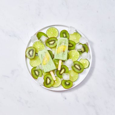 Donmuş diyet, sağlıklı meyve smoothies şeftali bir çubuk adet kivi, bir plaka üzerinde bir parça ile kireç ve buz küpleri a kopya-in metin için yer bir gri mermer masada. Düz yatıyordu