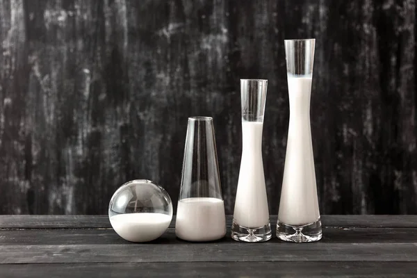 stock image Glass containers filled milk on a dark wooden table on a black background with place for text. Jewish holiday Shavuot concept.