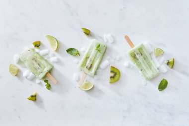 Dondurma kivi, nane ve limon meyve ve buz parçaları bir gri mermer zemin üzerine bir sopayla ayarlayın. Metin için yer. Düz yatıyordu