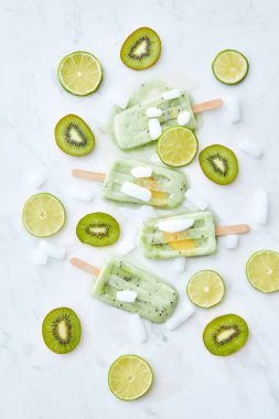 Dondurulmuş meyve suyu buz şeftali dilimleri bir parçası ile kivi ve beyaz zemin üzerine kireç parçaları yuvarlak. Gıda desen. Düz yatıyordu