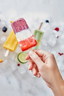 İştah açıcı meyve berry smoothies lolly donmuş buz küpleri ile meyve ve dondurma çerçevede kızın elini tutuyor. Sağlıklı tatlı. Düz yatıyordu