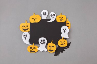 Gri bir arka plan, metin için yer üzerinde uçan hayaletler, ruhlar, korkunç kabaklar, siyah yarasalar gülerek el sanatları ile siyah kağıt yaratıcı kare kare.