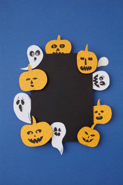 Tebrik kartı dekoratif el sanatları ile kağıt korkunç ruhlar ve hayaletler gülümseyen gülen ve kabak mavi Kağıt arka plan, metin altında yerleştirin. Üstten görünüm.