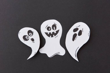 Dekoratif uçan uygulamasından şarkı hayaletler ve ruh bir siyah Kağıt arka plan üzerinde gülümseyen, yer altındaki metin. Cadılar Bayramı kavramı. Üstten görünüm.