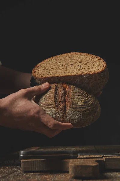 Крупным Планом Мужчина Пекарь Держит Руках Половинки Свежего Ржаного Хлеба — стоковое фото