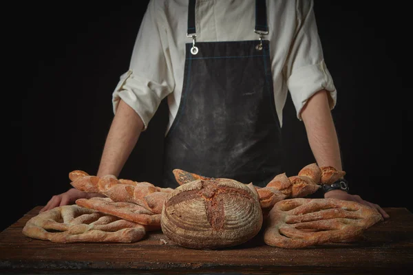 Mannen Bagare Med Mängd Bröd Ett Brunt Träbord — Stockfoto