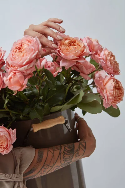 大きい花瓶のピンクのバラの花束は 灰色の背景に入れ墨のある女性の手によって開催されます 写真の表示に使用することができますまたはあなたのアイデアのモンタージュ — ストック写真