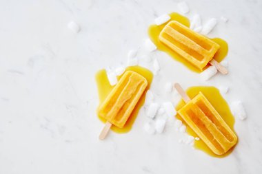 Su sıçramalarına ve eriyen dondurma meyve buz gri mermer arka plan metin için yer ile dilim bir sopayla gıda desen. Düz yatıyordu