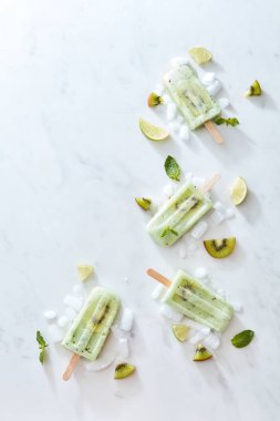 İce cream bir parça kivi ile bir sopa ve buz gri mermer zemin üzerine bir köşesinde kare şeklinde bileşimi. Metin için yer. Fikirlerinizi için düzen. Düz yatıyordu