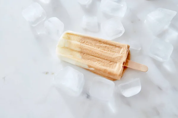 氷の上のビーガン バナナ コーヒー クリーム乳製品無料アイス アイスキャンディー大理石の背景 夏のデザート — ストック写真