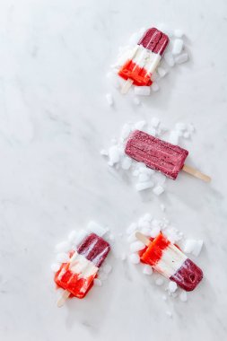 Dört çok renkli meyve dondurma lolly buz küpleriyle kopya alanı bir gri mermer zemin üzerine bir köşe çerçeve şeklinde sunulan kümesi. Düz yatıyordu