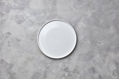 El yapımı porselen boş yuvarlak alan bir kopyasını gri bir beton zemin üzerine bir tabak. Ürün montaj veya görüntü için kullanılabilir. Düz yatıyordu