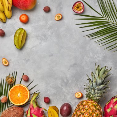 Çeşitli sulu egzotik meyveler, Hindistan cevizi, lychee, carom, ananas ve palmiye yaprakları metin için yer bir gri beton zemin üzerine. Yemek düzeni. Düz yatıyordu