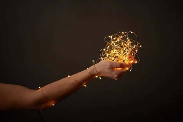 Mano Una Chica Sostiene Montón Guirnaldas Brillantes Alrededor Fondo Oscuro — Foto de Stock