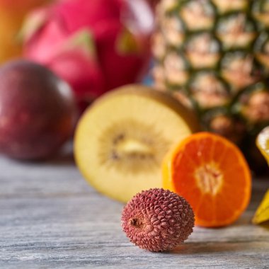 Egzotik olgun lichi meyve karışımı tropikal meyve ananas, kivi, dragon meyve kopya alanı gri bir ahşap zemin üzerine arka plan bulanık. Sağlıklı diyet gıda kavramı.
