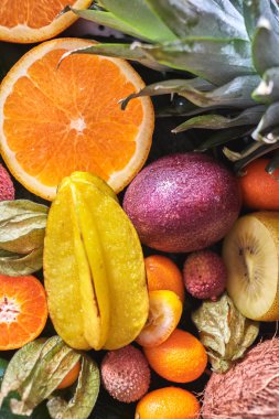Bir backgraund olarak taze sulu tropikal meyve. Passion fruit, carambola, Çin, Kamkat, portakal tatlısı, phisalis yeşil yaprakları üzerinde. Yakın çekim. Üstten görünüm. Sağlıklı diyet gıda kavramı.