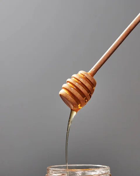 Γλυκό Μέλι Στάζει Ένα Βάζο Φρέσκα Βιολογικά Σιρόπι Ένα Γκρίζο — Φωτογραφία Αρχείου