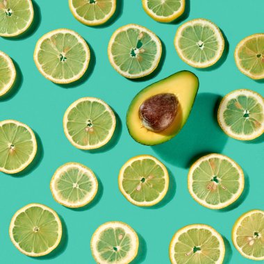 Meyve narenciye limon dilimleri desen avokado yarısını ile açık yeşil arka planı üzerinde gölgeler yaz. Sağlıklı diyet gıda kavramı. Üstten görünüm.