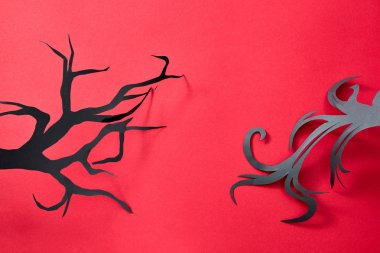 Siyah el sanatları kağıt ağaç dalları üzerinde metin için yer ile kırmızı bir arka plan deseni. Mistik Cadılar Bayramı kartpostal. Düz yatıyordu