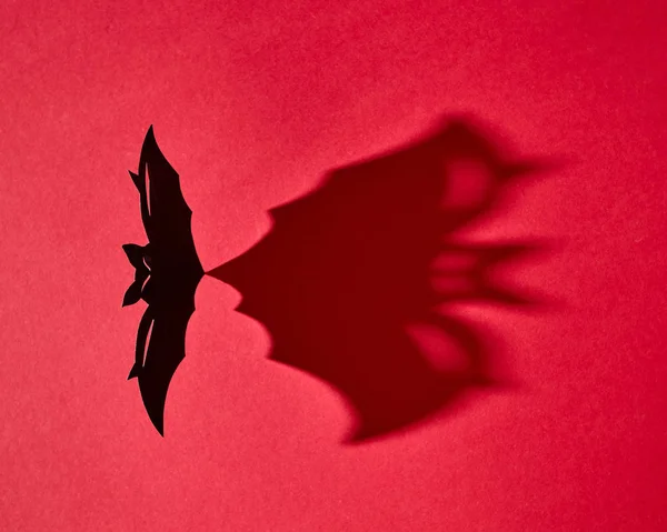 赤い背景とコピー領域に影を黒の手作りクラフト紙バット 創造的な神秘的なハロウィン カード フラットを置く — ストック写真