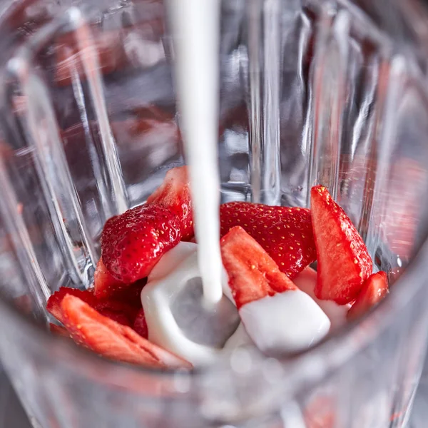 牛奶被倒进一个盛有有机草莓片的搅拌机里 一步一步烹饪自制奶昔 顶视图 — 图库照片
