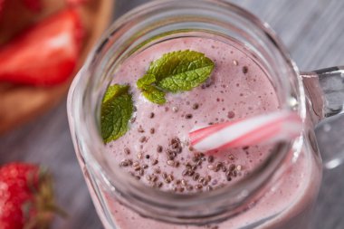 Nane yaprakları ve gri bir ahşap zemin üzerine chia tohum ile vitamin sütlü berry güler yüzlü closeup. Sağlıklı içecek. Üstten görünüm